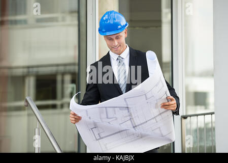 Young Engineer With Hard Hat Holding Blueprint In His Hands Stock Photo