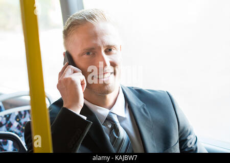 Smiling Businessman Travelling In Tram Talking On Cellphone Stock Photo