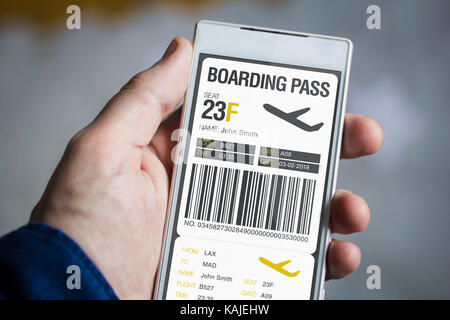 man hand holding boarding pass smartphone. All screen graphics are made up. Stock Photo