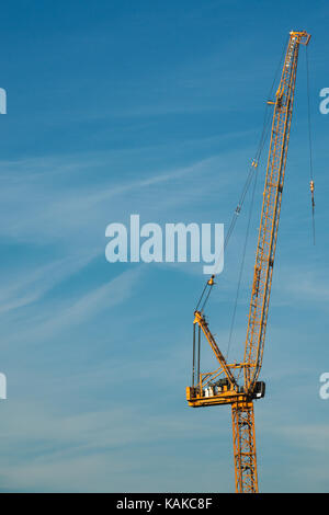 Two Tall Cranes on Construction Building Site, Yellow on Blue Sky Background Stock Photo