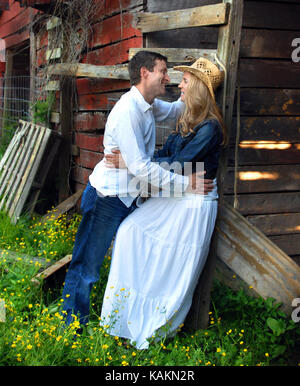 Young couple discuss their future plans as they enjoy special romantic moments around a rustic barn.  They are holding each other and looking into eac Stock Photo