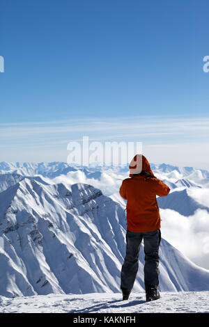 Skier makes photo on top of snow mountains at nice sun day. Caucasus Mountains in winter, Georgia, region Gudauri. Stock Photo