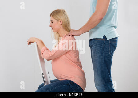 Midsection of man giving shoulder massage to pregnant woman over white background Stock Photo