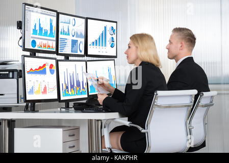 Young financial analysts using computers at desk in office Stock Photo