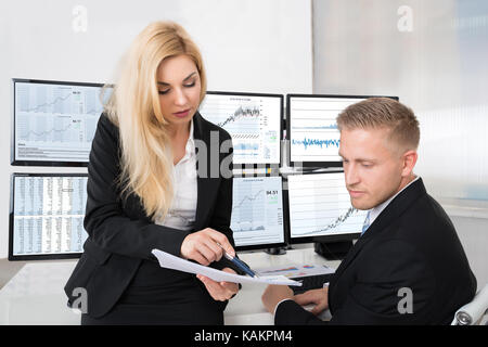 Young financial analysts discussing over documents in office Stock Photo