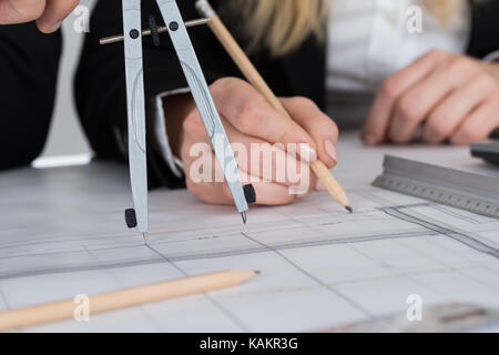 Cropped image of young architects working on blueprint at desk in office Stock Photo