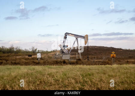 A gray oil rig pumping oil in a deserted field Stock Photo