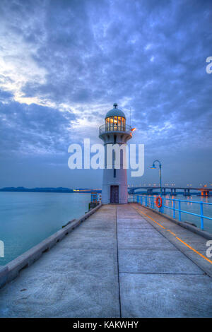 Nightfall on Singapore lighthouse at Tuas Link in the West during sunset blue hour overlooking the Johor Straits toward Malaysia in the north. Stock Photo