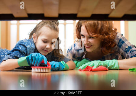 Mother and daughter do the cleaning in the house. Happy woman and little child girl wiped the floor. Stock Photo