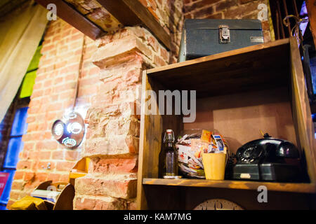 The view of the wooden wardrobe with the leather suitcase, antique phone placed near the brick wall decorated with colander. Stock Photo