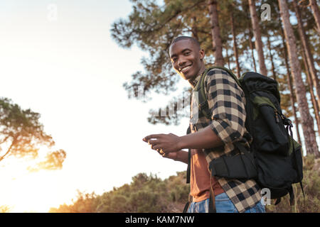 Smiling young African man using gps while out hiking  Stock Photo