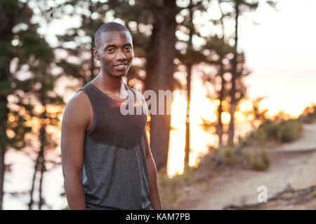 Smiling African man standing on a trail while out jogging Stock Photo