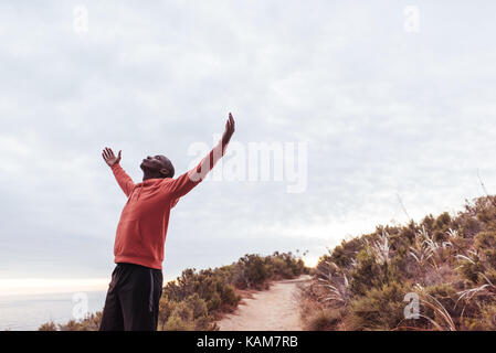 Young man standing on a trail outdoors embracing nature  Stock Photo