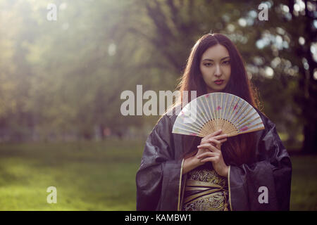 Portrait of young beautiful Asians in a grey kimono and with a fan Stock Photo