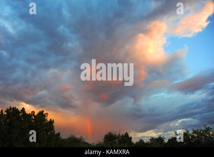 Rainbow appears in the sunset sky over Phoenix, Arizona.  Blue merges with pinks and orange as light fades. Stock Photo