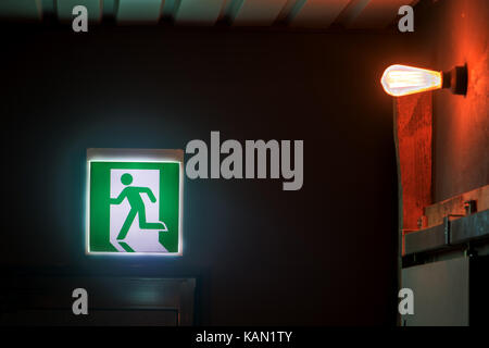 The emergency exit sign shows the direction of escape in case of danger. The emergency exit board over door in corridor inside the building. Stock Photo
