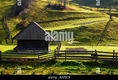 woodshed near the fence on grassy hillside. beautiful rural scenery in autumn Stock Photo