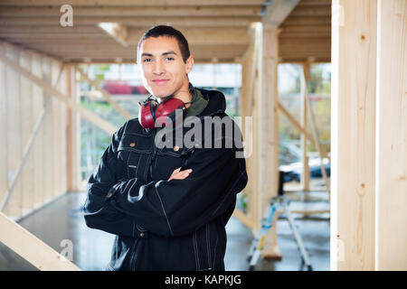 Carpenter Smiling While Standing Arms Crossed At Site Stock Photo