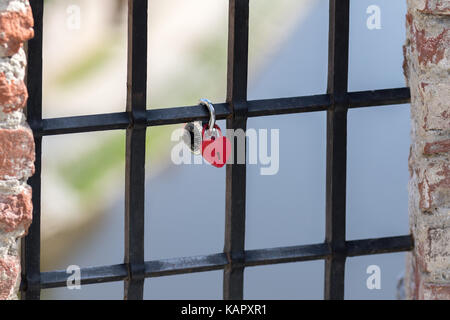 Cesky Krumlov, Czech Republic - August 17, 2017: Red heart-shaped padlock is chained to an inferno on the river in the historic city center Stock Photo