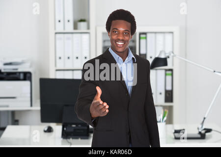 Portrait of confident young businessman offering handshake in office Stock Photo