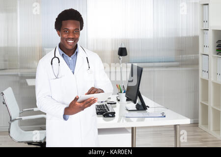 Portrait of confident young doctor using digital tablet in clinic Stock Photo