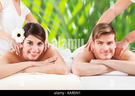 Portrait of happy young couple receiving shoulder massage at spa Stock Photo