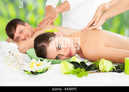 Portrait of smiling young couple receiving back massage at beauty spa Stock Photo