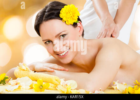 Portrait of beautiful young woman receiving back massage from massager at beauty spa Stock Photo