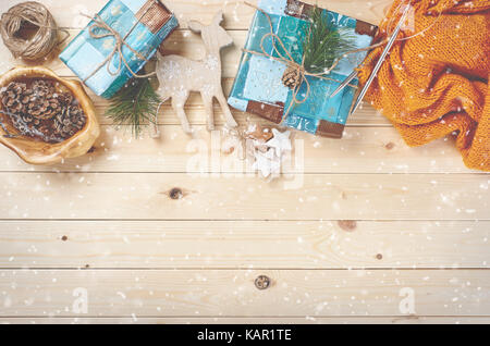 Top view of Christmas background on wooden desk with fir, snow, handmade knitwear and gift boxes. Copy space. Stock Photo