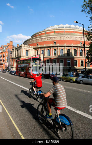 Tourists on rental bike passing by Royal Albert Hall. London's bicycle sharing scheme launched with 6000 bikes on 2010 to help ease traffic congestion Stock Photo