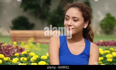 Young Woman Sitting In Flower Garden Stock Photo