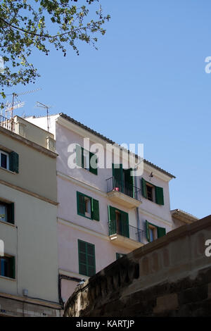 PALMA DE MALLORCA, BALEARIC ISLANDS, SPAIN - MARCH 29, 2017: Residential pink building with green window shutters and curved stone structure detail in Stock Photo