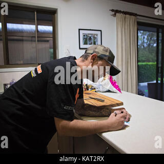 Man writing reminder note and putting on fridge Stock Photo