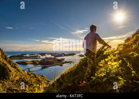 Male hiker going to the top of mount Festvagtinden with views over the village of Henningsvaer on Lofoten islands in Norway
