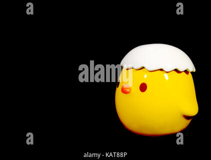 Vibrant Yellow Little Bird Ceramic Doll Isolated on Black Background Stock Photo