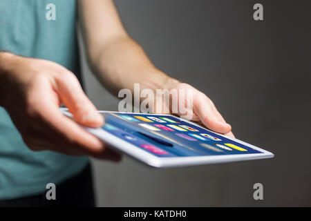 View of a Hand holding black tablet with operating system screen Stock Photo