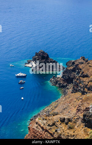Boats in the sea near the coast of Oia village on Santorini island, Greece Stock Photo