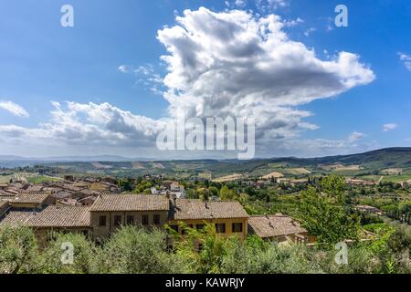 Horizontal photo with few rustic houses which are built on side of historic town in Tuscany Italy. The landscape with hills, rocks, olive trees and fo Stock Photo