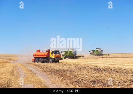 TERNOPIL - JULY 20: A few combines cutting a swath through the middle of a wheat field during harvest on July 20, 2017, in Ternopil Stock Photo