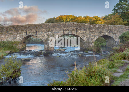 arched stone bridge over East Dart River at sunrise at Postbridge, Dartmoor National Park, Devon, UK in September Stock Photo