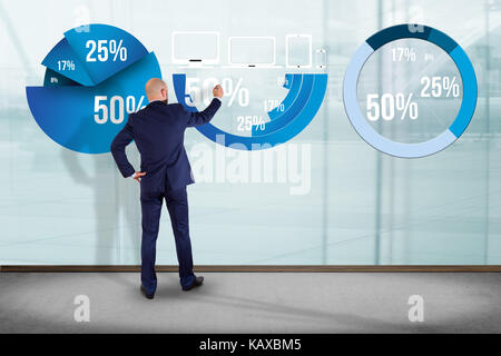 View of a Businessman in front of a wall writing on a statistics interface - business concept Stock Photo