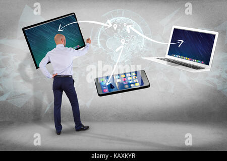 View of a Businessman in front of a wall with Computer and devices displayed on a futuristic interface with interantional network - Multimedia and tec Stock Photo