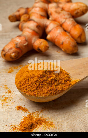 Spoonful turmeric powder with a fresh root at the background Stock Photo