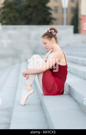 A girl is sitting on the steps in a ballet dress Stock Photo