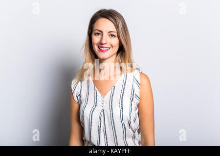 Young Woman Leaning Against Gray Wall Background Stock Photo