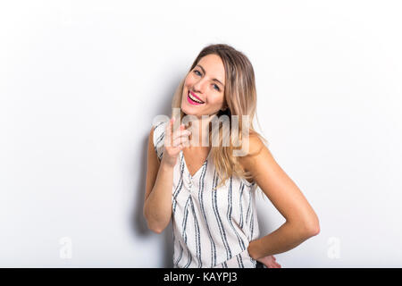 Young Woman Leaning Against Gray Wall Background Stock Photo