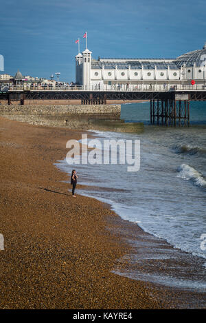 Woman standing on the beach and Brighton Palace Pier, Brighton, England, UK Stock Photo