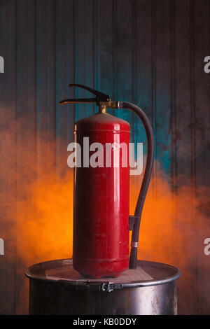 Red fire extinguisher on urban style background with orange smoke Stock Photo