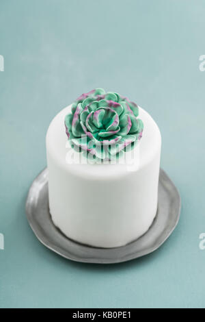 White mini wedding cake covered with fondant with gum paste succulent on a pewter plate Stock Photo
