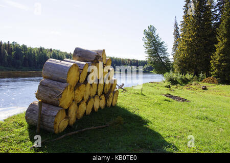 Stacks of spruce firewood in the background of the taiga and the Siberian rivers Stock Photo